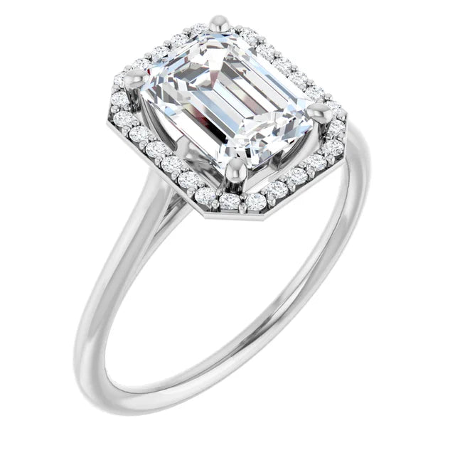 Emerald engagement ring with halo and intricate band in white gold