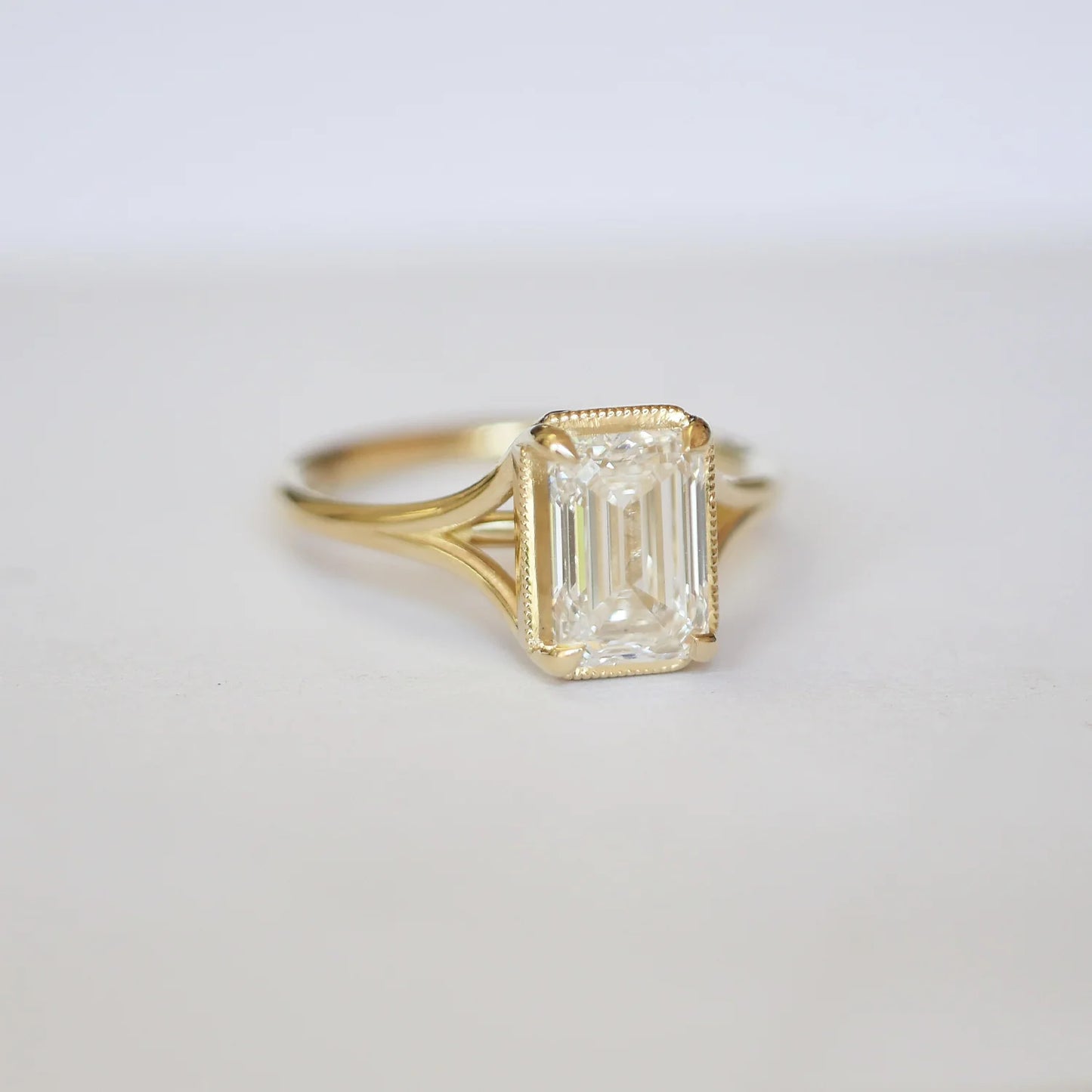 Elegant Split Shank Emerald Solitaire Ring in yellow gold with diamond