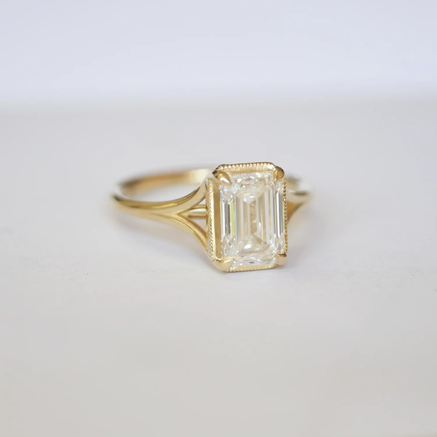Elegant Split Shank Emerald Solitaire Ring in yellow gold with diamond